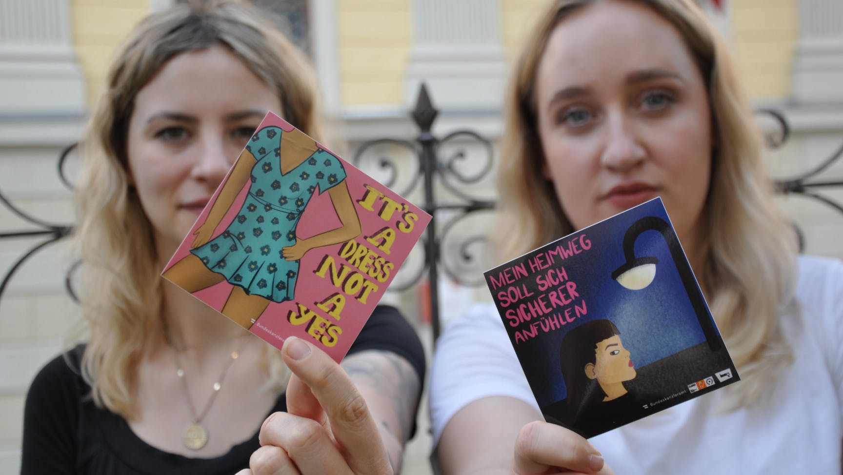 Zwei junge Frauen halten jeweils einen Sticker in die Kamera.