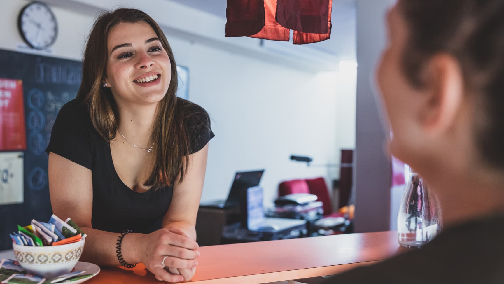 Junge Frau lehnt sich über die Bar und spricht