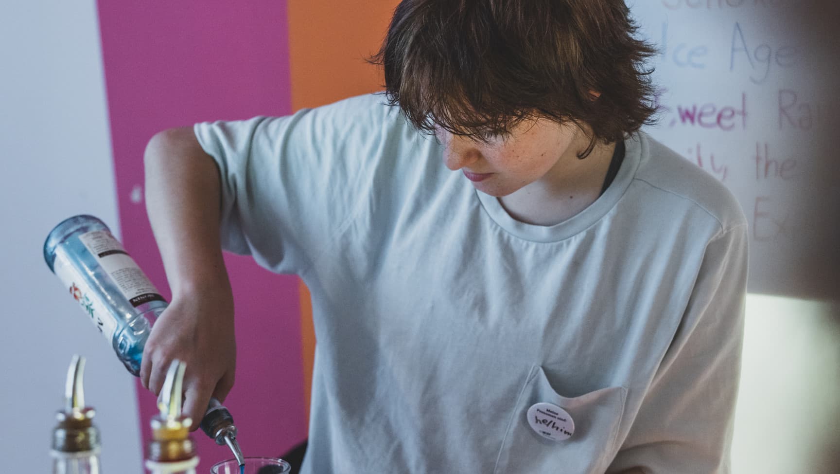 eine junge Person schenkt hinter der Bar Cocktails ein