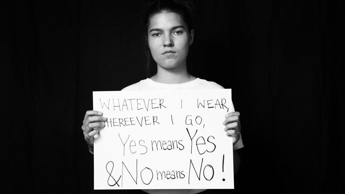 Eine junge Frau hält ein Schild auf dem steht: Whatever i wear, wherever i go, yes means yes & no means no!