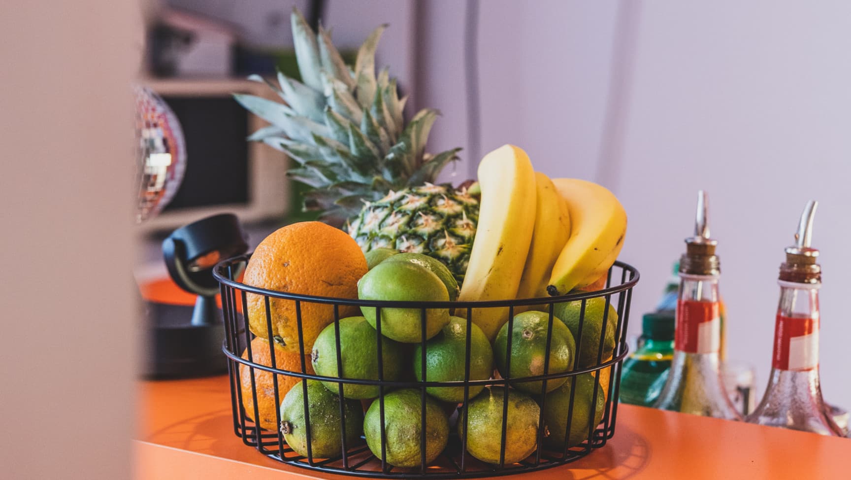 Ein Obstkorb gefüllt mit Früchten auf einer orangen Theke.