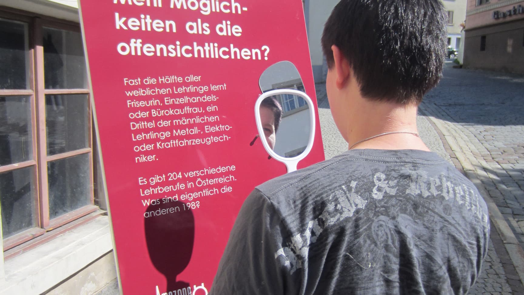 Person steht vor einem Aufsteller mit der Aufschrift "Mehr Möglichkeiten als die offensichtlichen?"