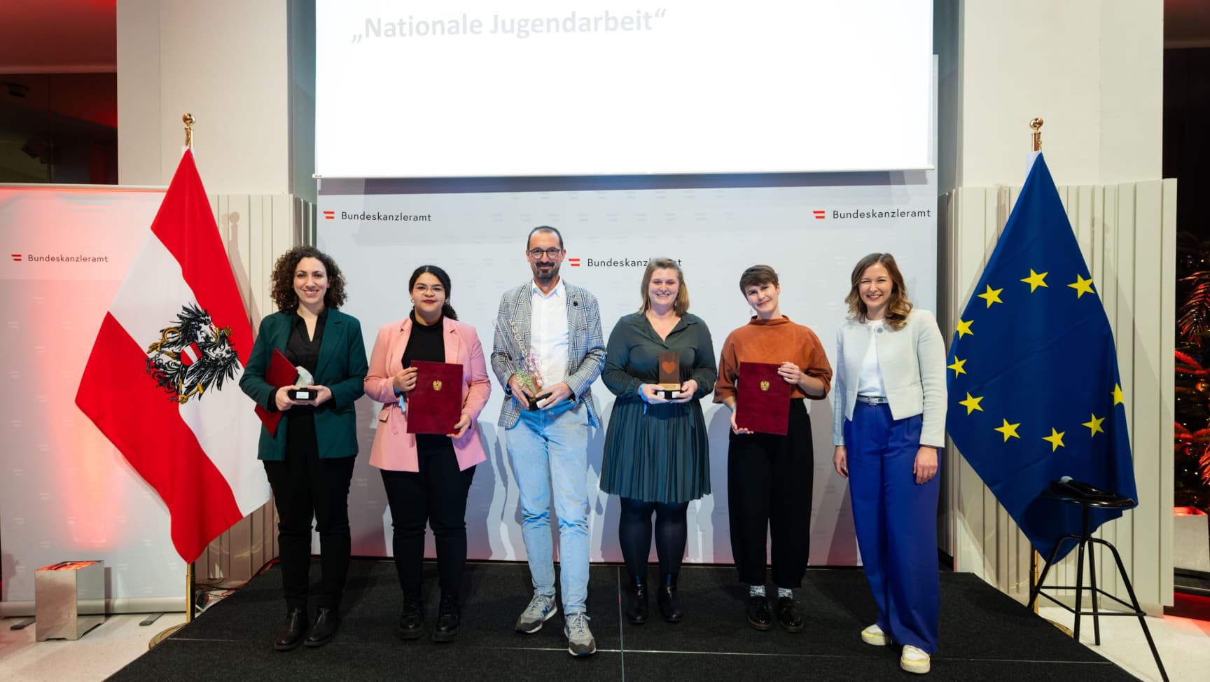Fünf Preisträger*innen und Staatssektretärin Plakolm auf der Bühne.