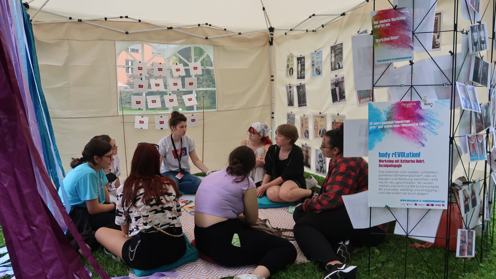 Workshopsuation in einem Zelt mit Workshopleitung und Teilnehmerinnen*