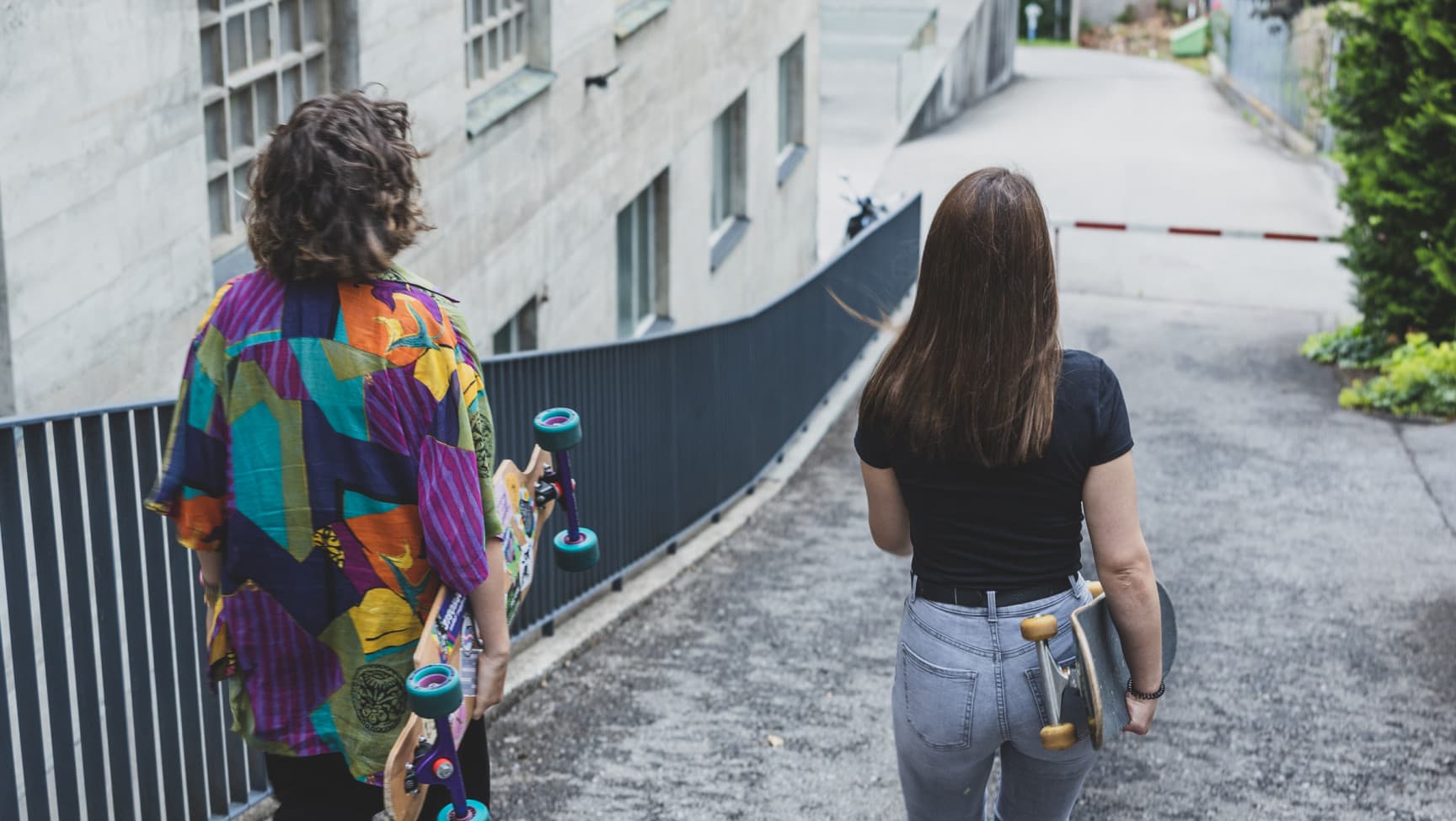 Zwei Jugendliche laufen mit den Skateboards in der Hand eine Straße hinunter.