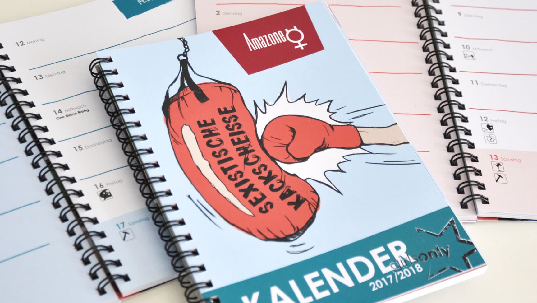 Kalender liegen auf. Auf dem Cover ist eine Grafik mit Boxhandschuh und Boxsack auf dem steht "Sexistische Kackscheiße"