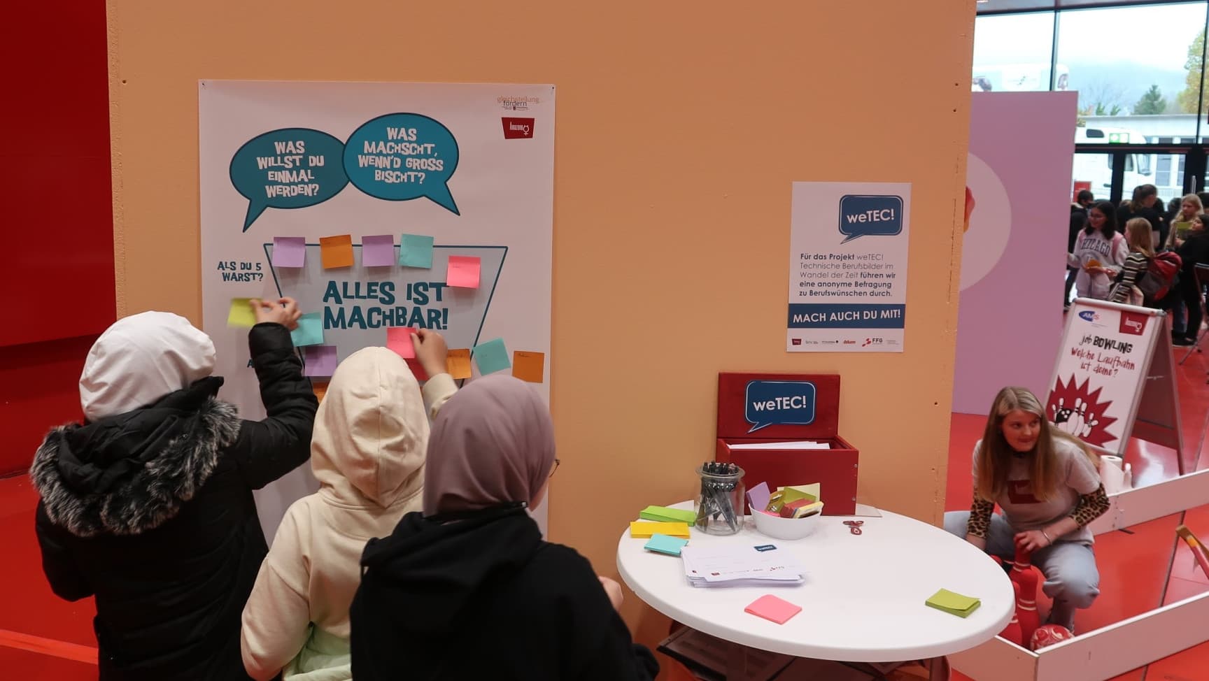 Drei Jugendliche kleben Post-Its auf ein Plakat.