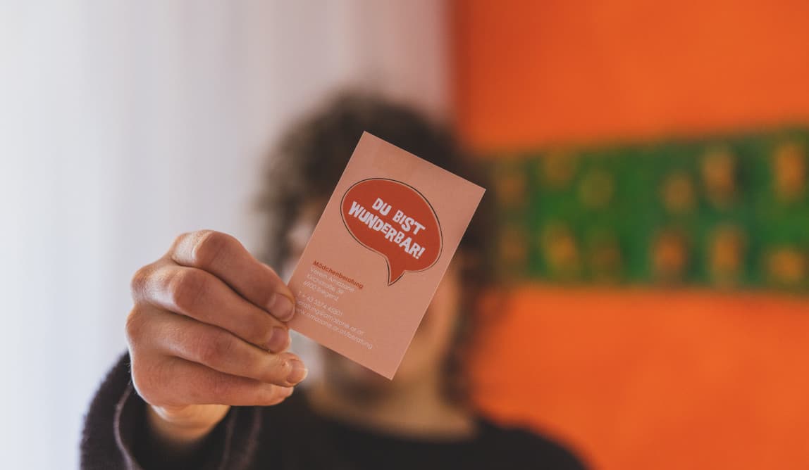 Eine Person hält eine orange Karte mit der Aufschrift „Du bist wunderbar“ in die Kamera.