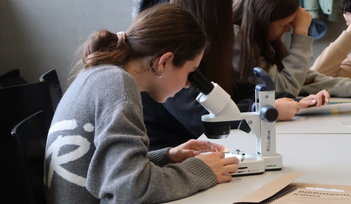 Eine Jugendliche schaut durch ein Mikroskop.
