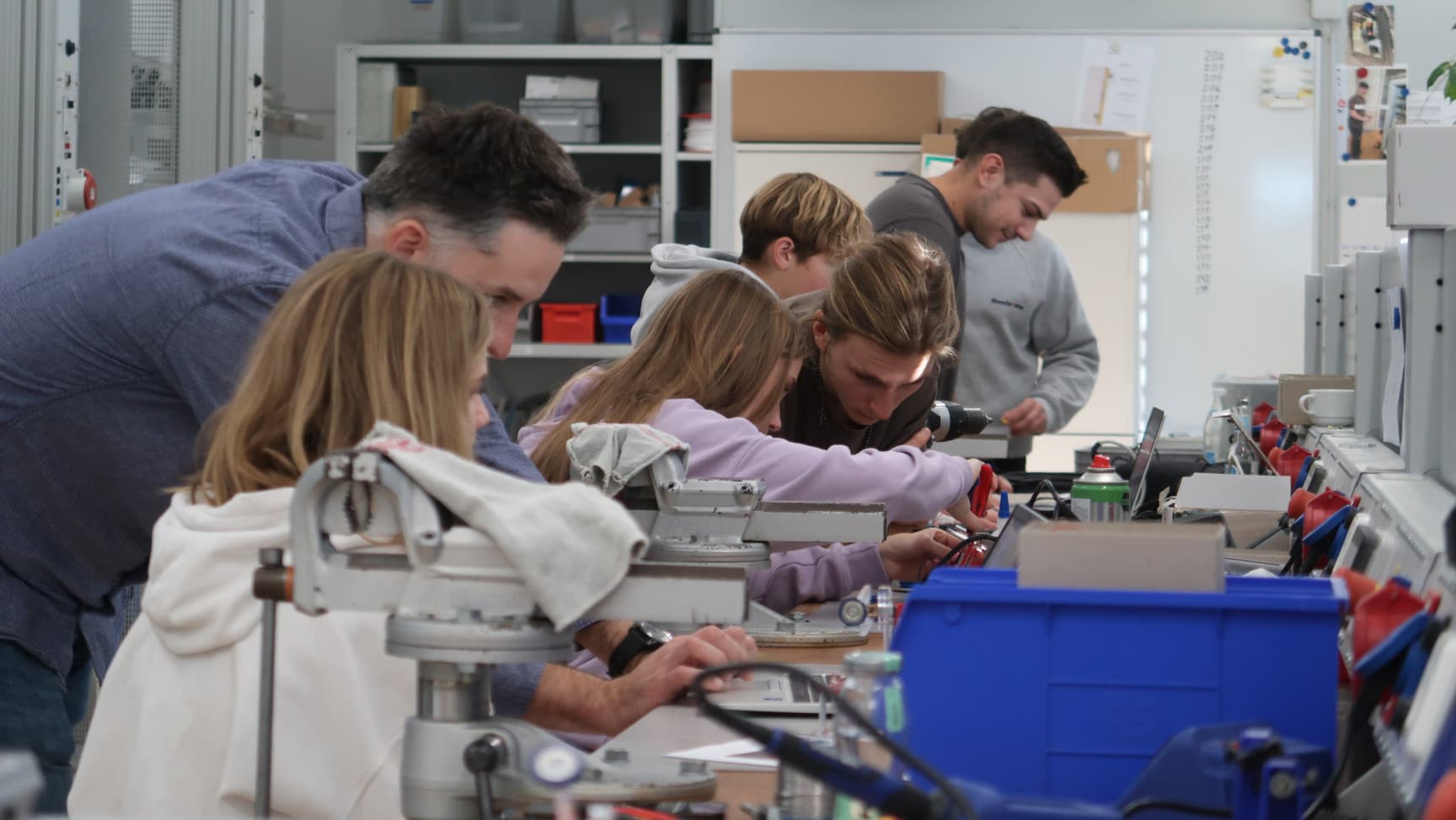 Mehrere Personen an einer Werkbank, die am arbeiten sind.