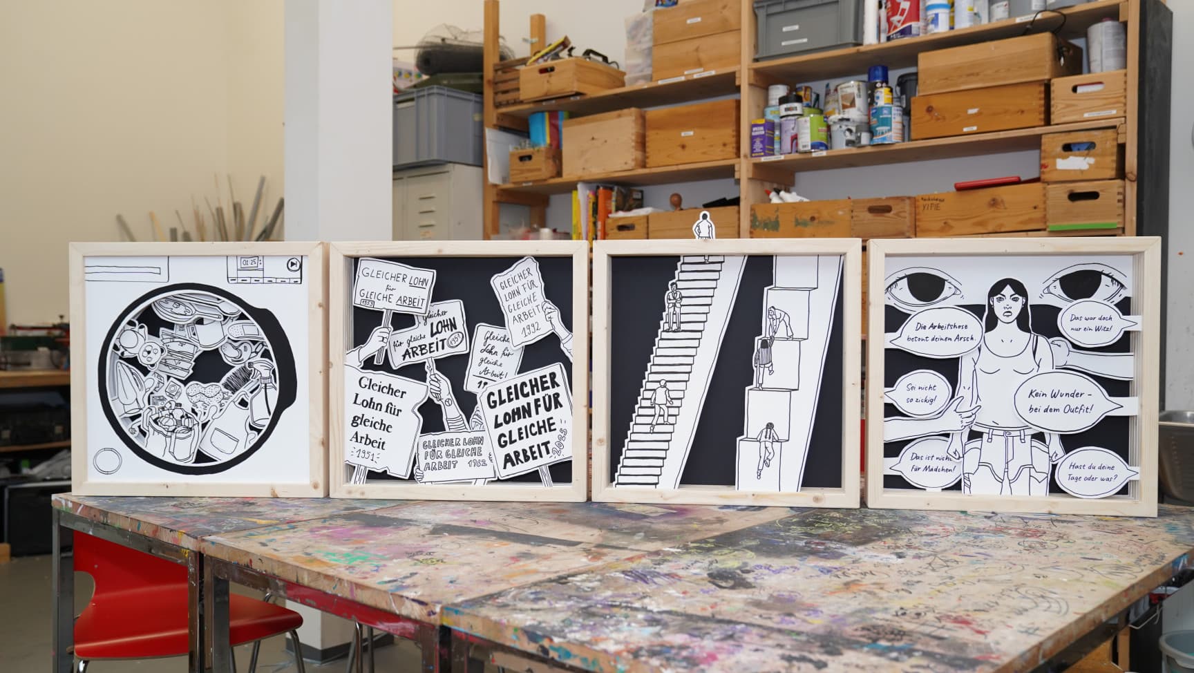 Vier Bilderrahmen mit schwarz/weiß Illustrationen stehen auf einem Tisch in einer Werkstatt
