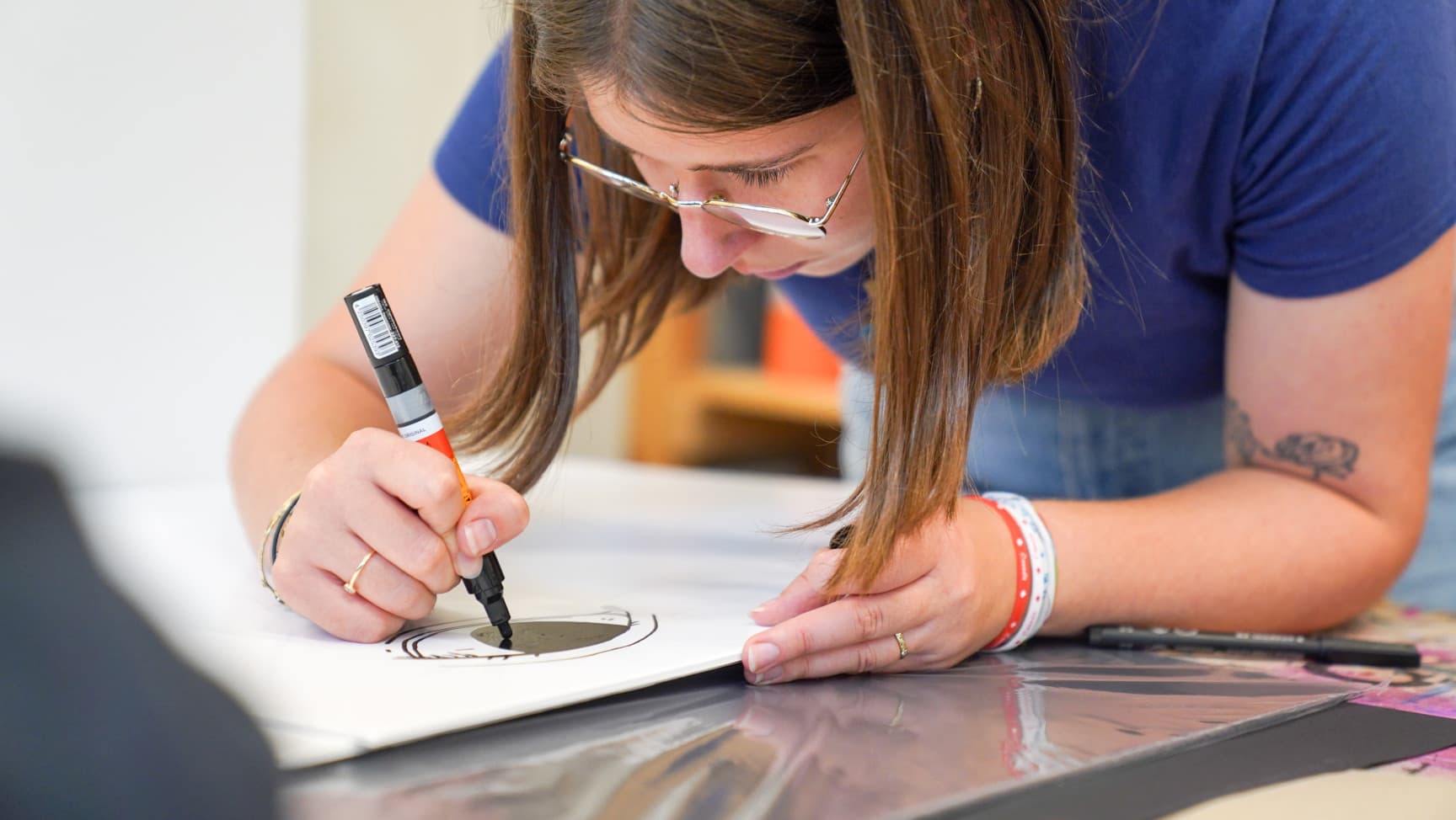 Junge Person zeichnet mit dickem Stift auf eine weiße Platte