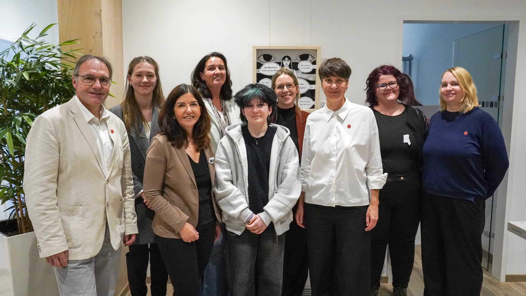 Neun Personen stehen vor einem Bild