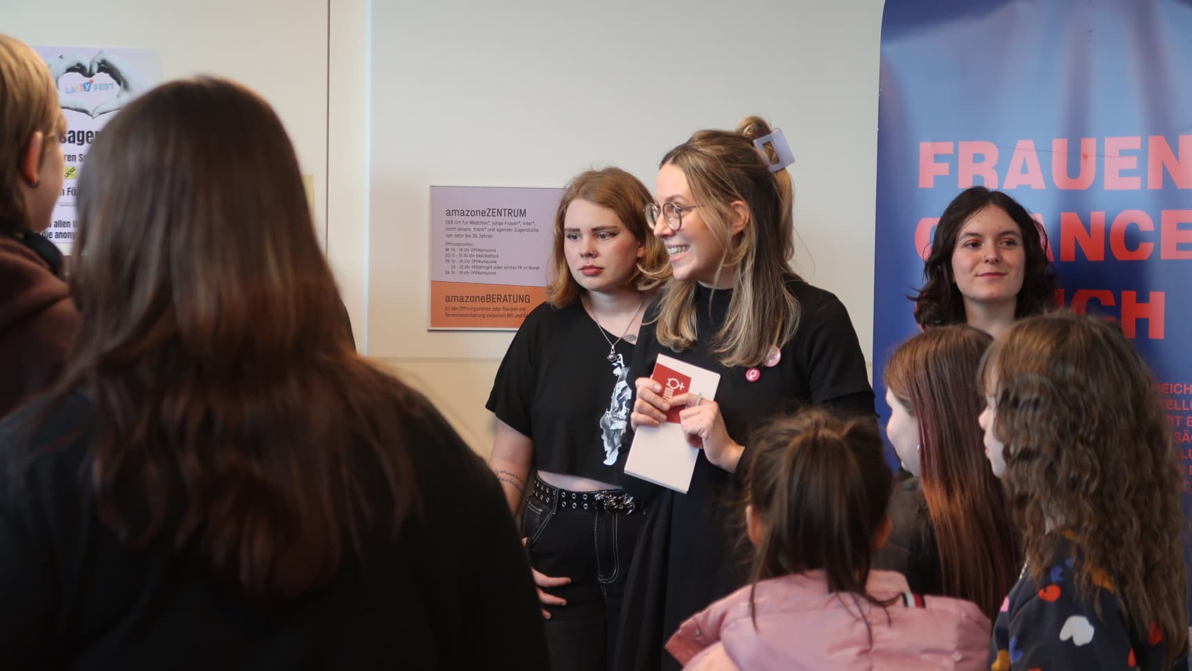 Frauen und Mädchen stehen vor einem Rollup