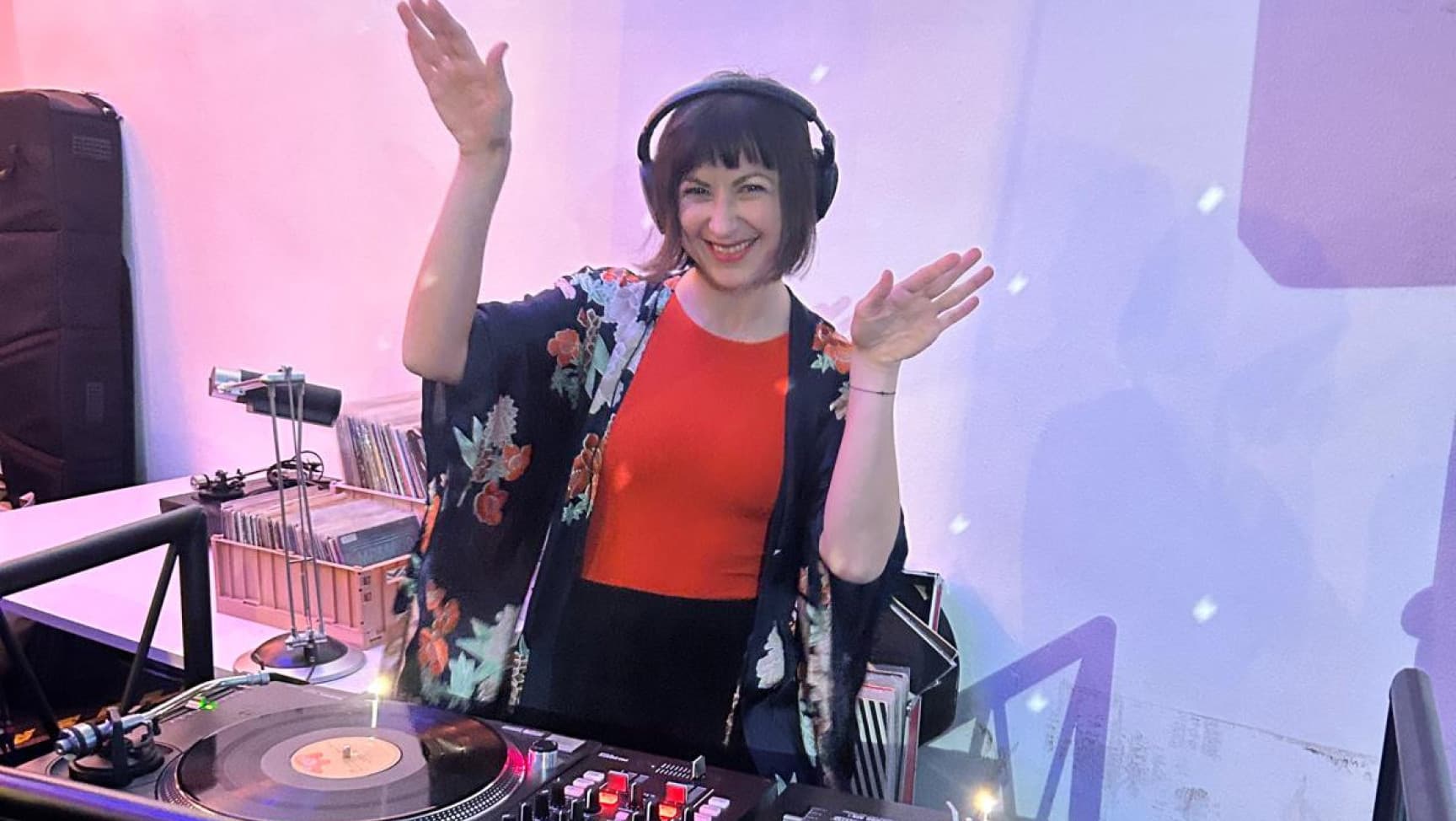 DJane mit Kopfhörern tanzend hinter Plattenspieler