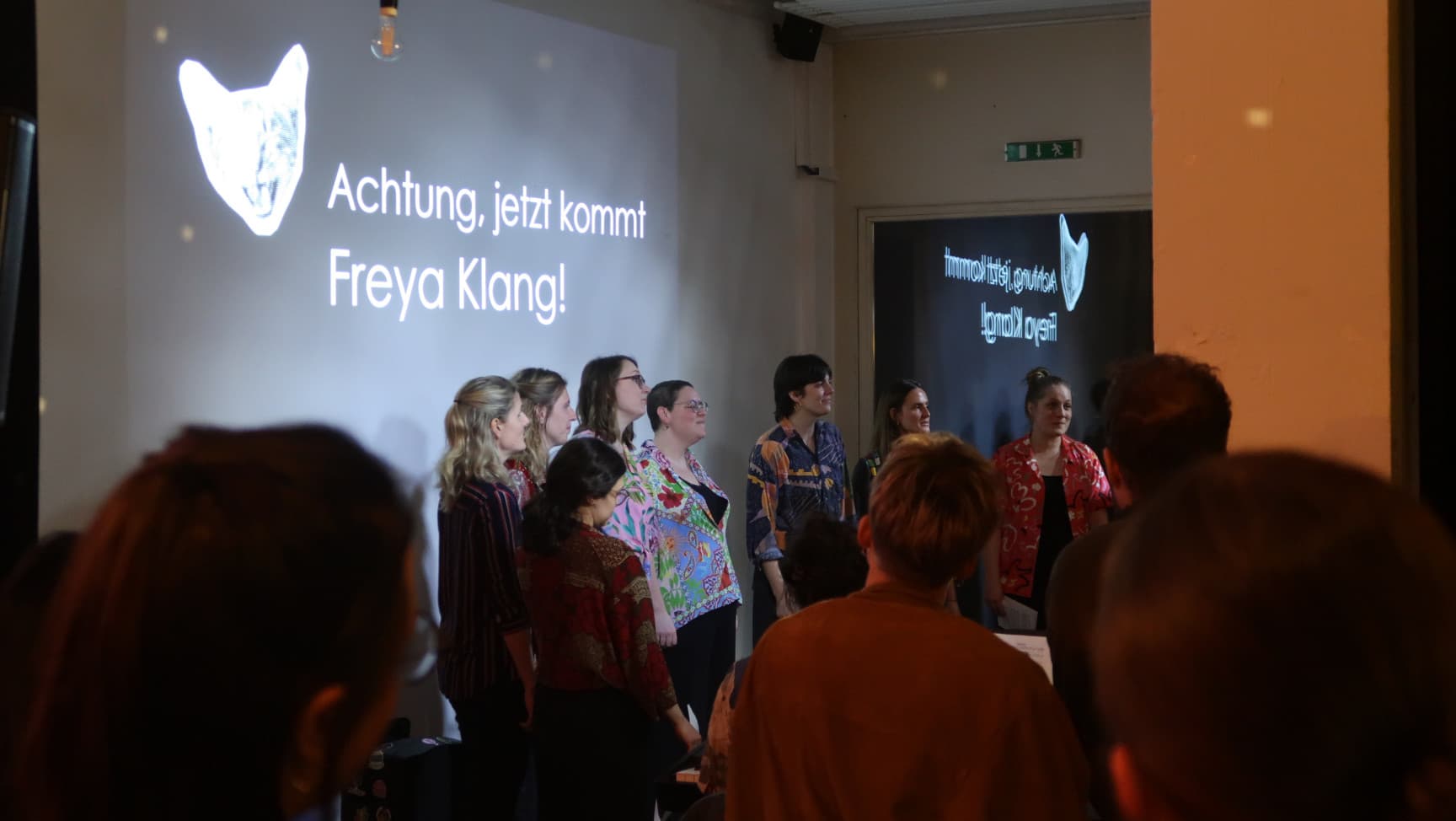 Chor und Publikum. Auf der Wand steht: Achtung, jetzt kommt Freya Klang!