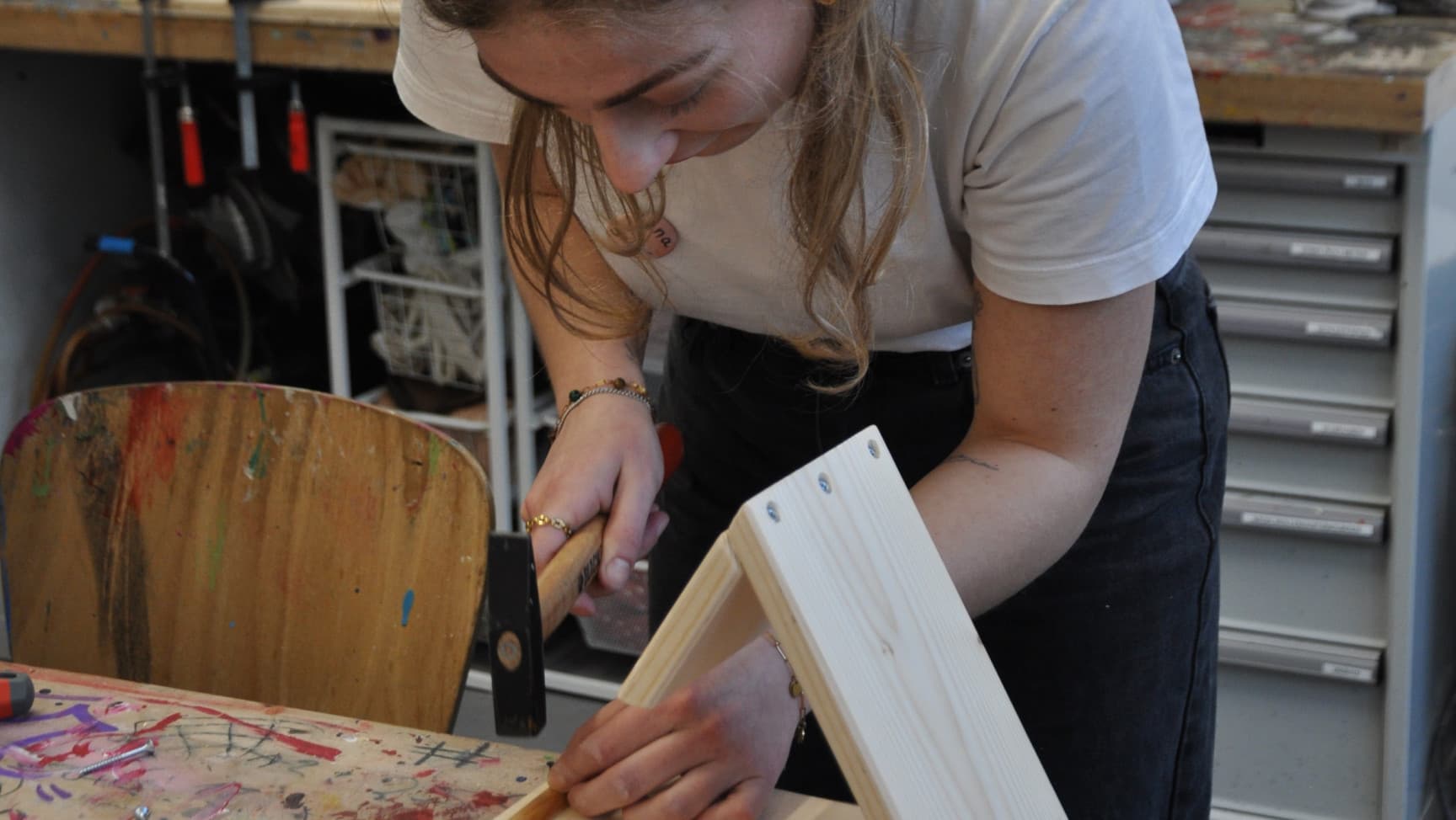 eine junge Frau mit Hammer baut ein Gebilde aus Holz