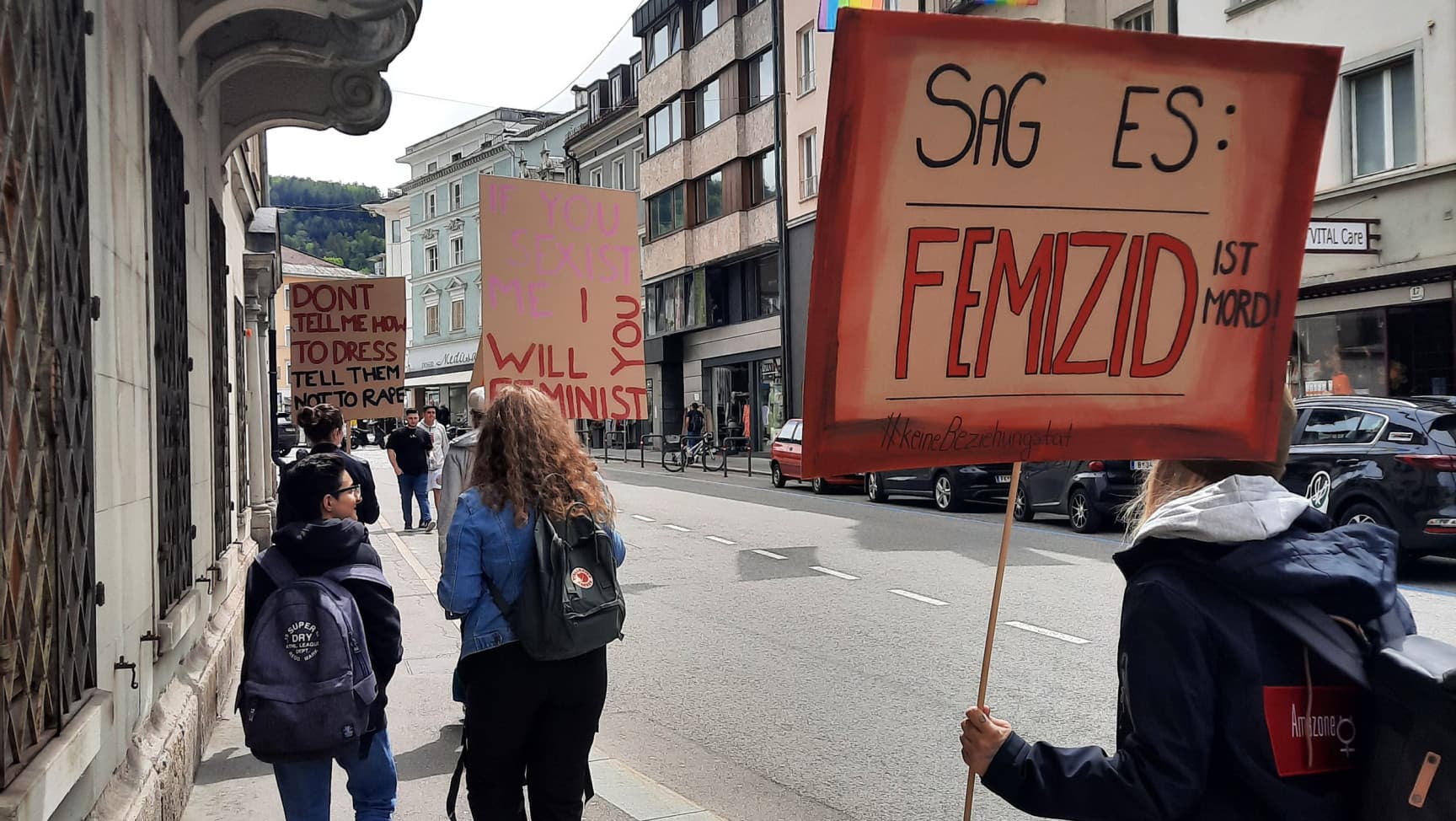 Demonstrationszug mit Schildern und Regenbogenfahnen