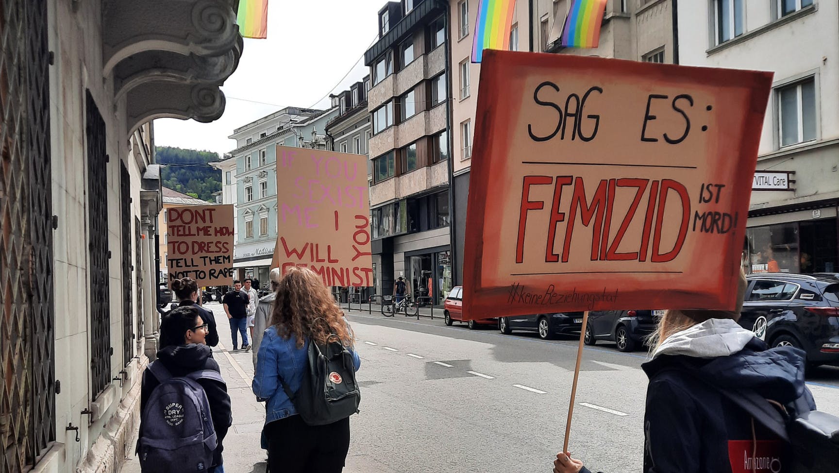 Demonstrationszug mit Schildern und Regenbogenfahnen