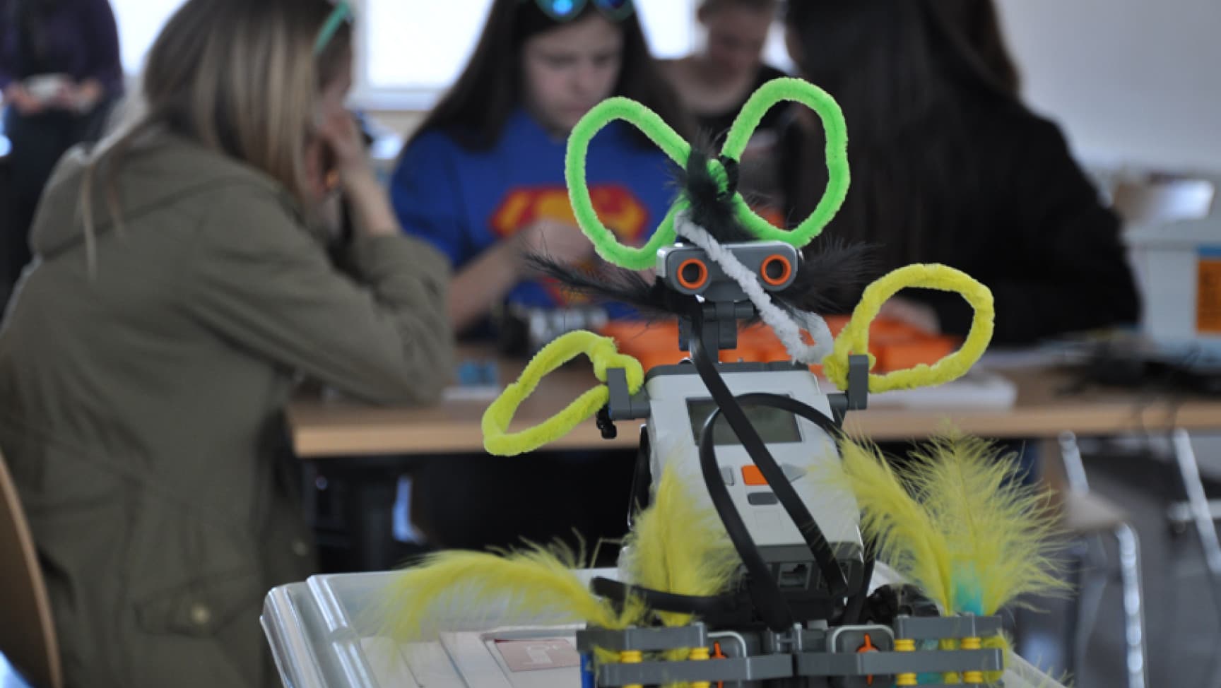 Eine Roberta im Vordergrund, dahinter eine sitzende Personengruppe.