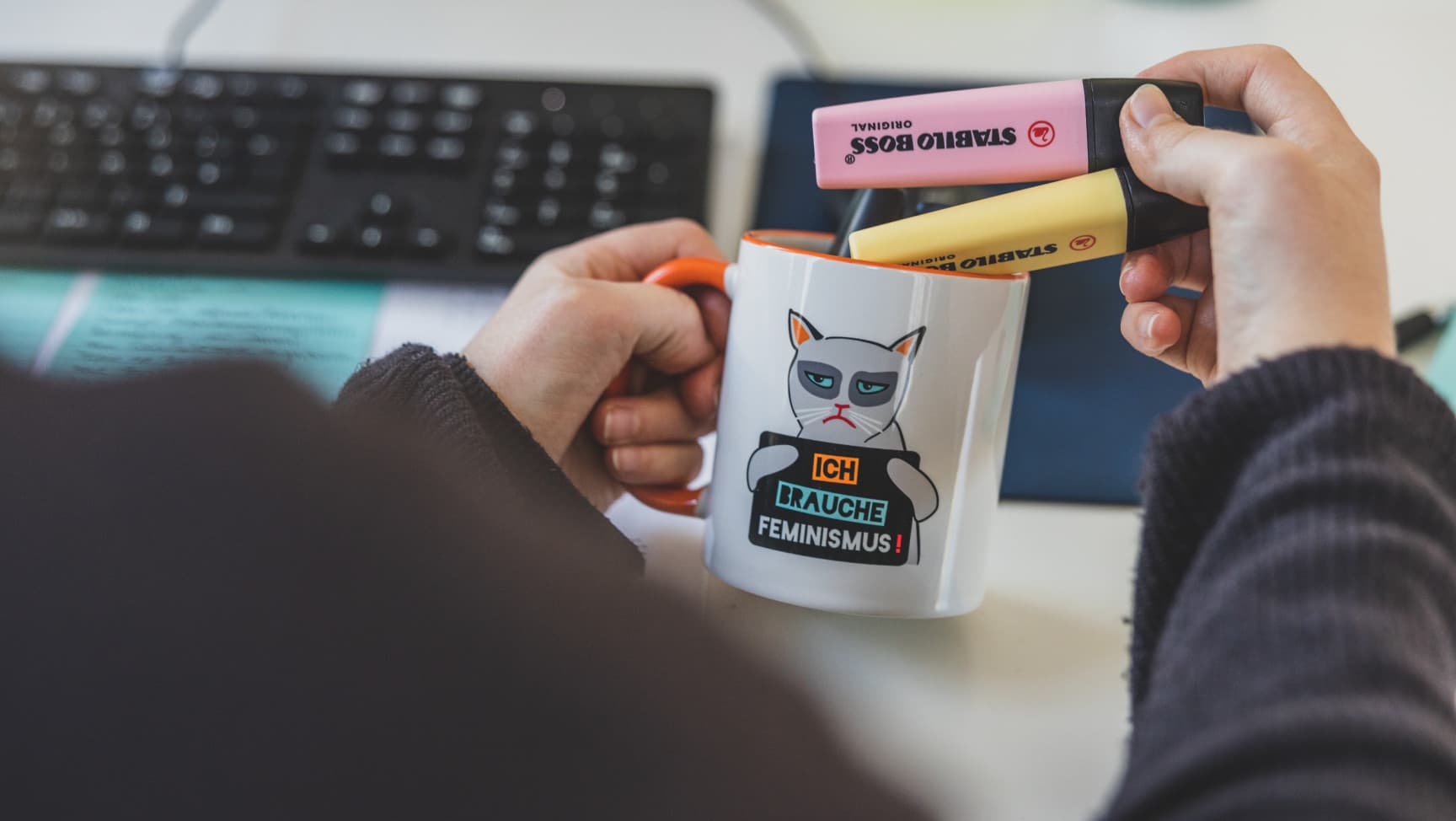 Eine Person nimmt Stifte aus einer Tasse auf der steht: Ich brauche Feminismus!
